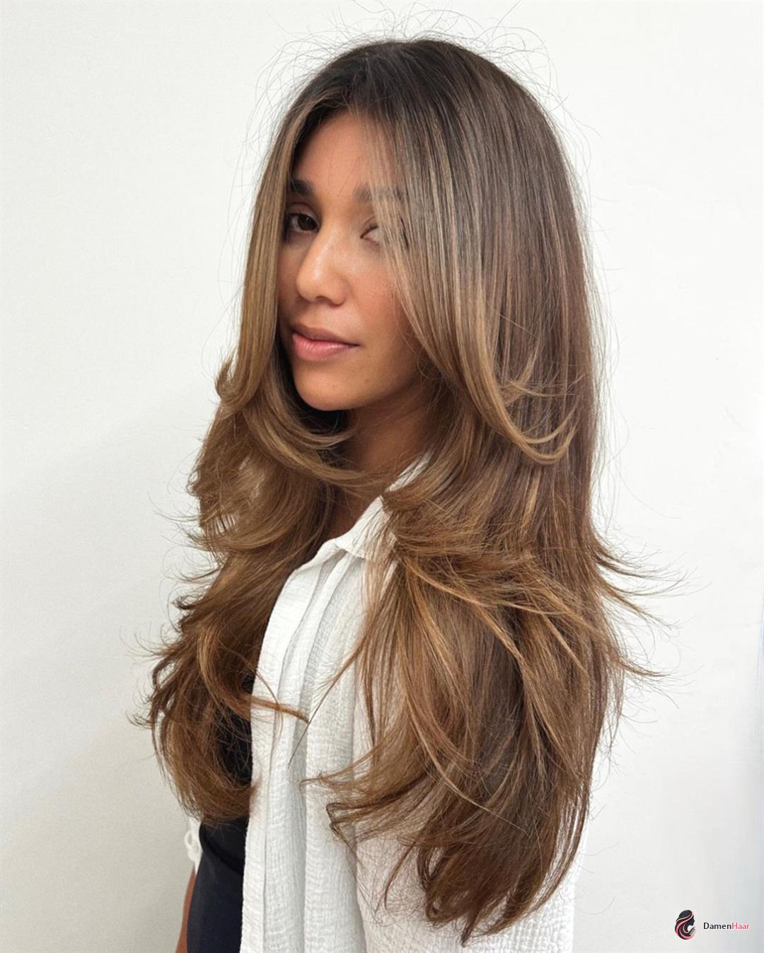 Eleganter Langhaarschnitt mit warmen Babylights Lange glatte Stufen mit karamellfarbener Balayage